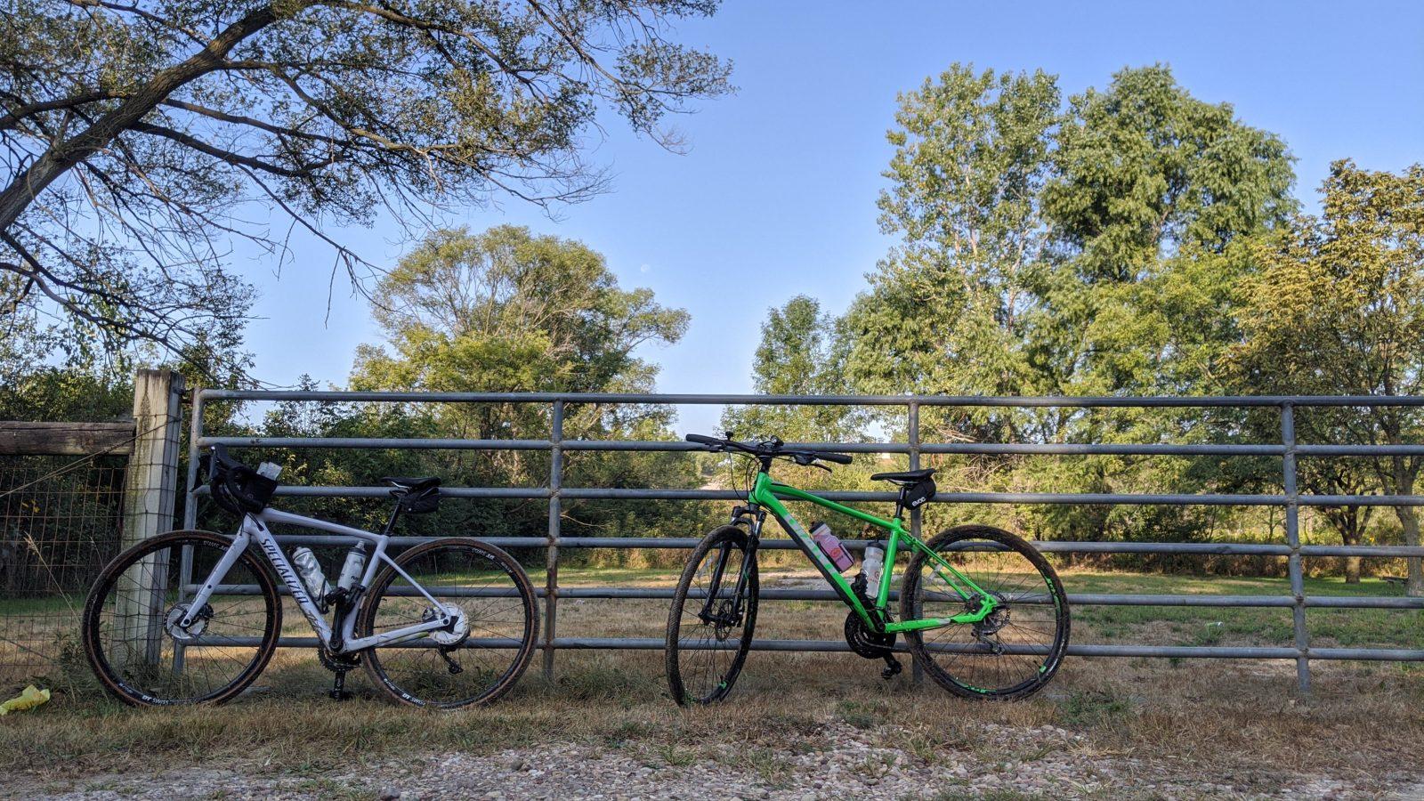 a gravel bike and a crossover bike standing against an iron gate at lake cunningham in omaha, nebraska