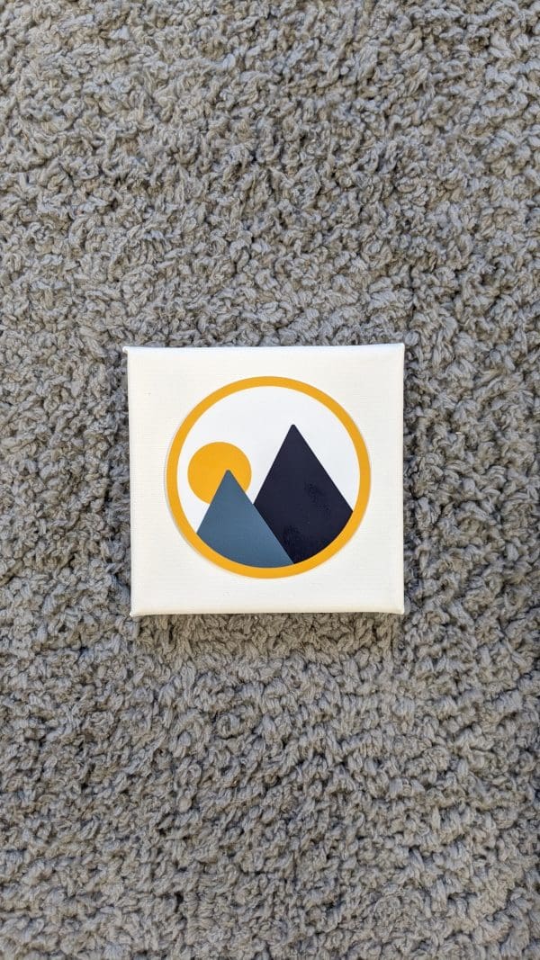 monolith trail co brandmark circle sticker on top of a small square canvas on gray carpet