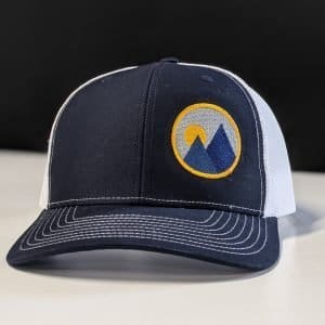 product shot of monolith trail co trucker hat in navy with the brandmark on one panel